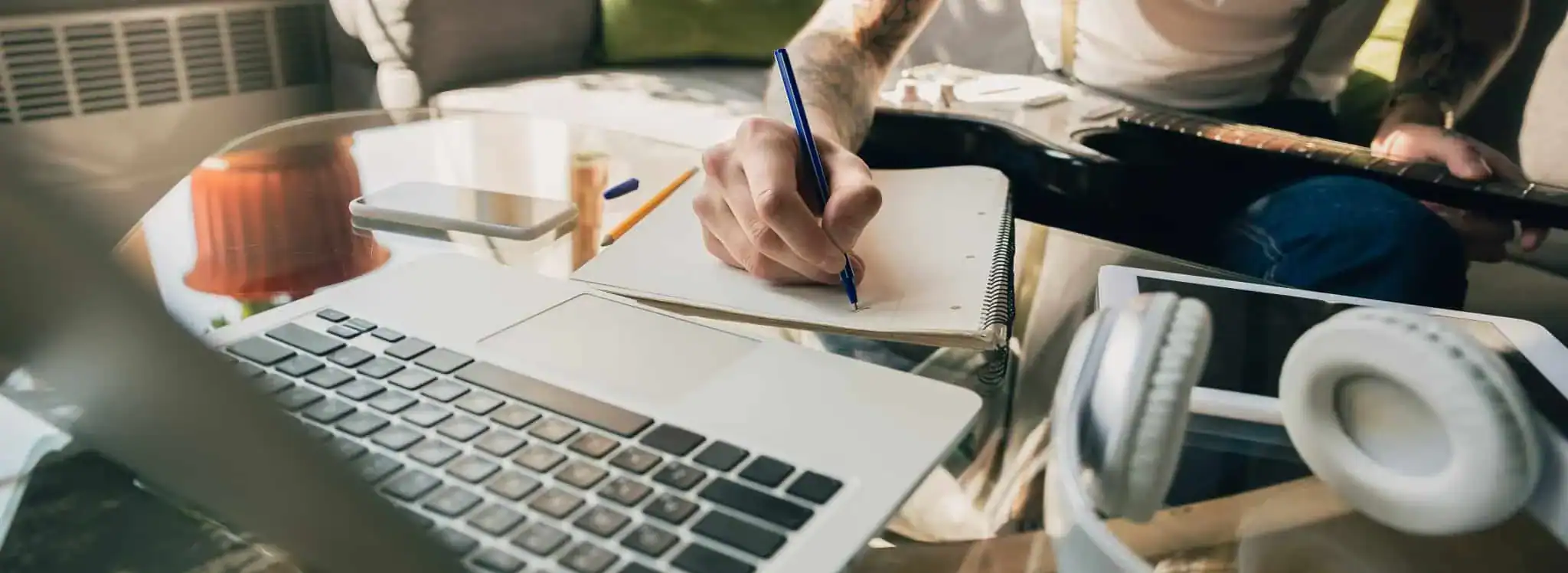 Análise de Cursos online representada por pessoa anotando em caderno ao lado de notebook e fones de ouvido, simbolizando estudo, avaliação e aprendizado digital.